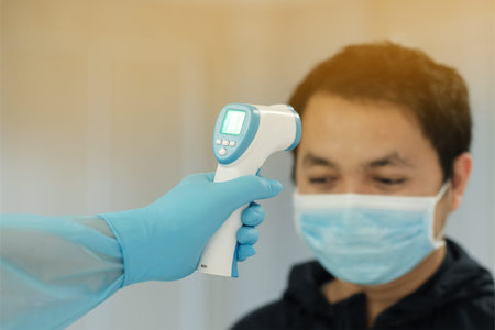 Medical staff use infrared forehead thermometer for check body temperature, Covid-19 outbreak conceptの写真素材