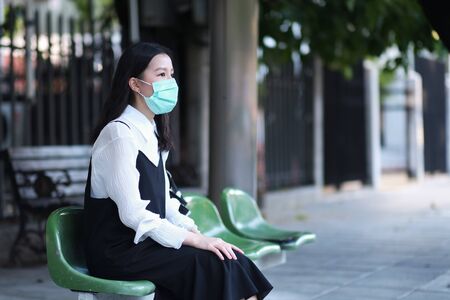 Asian women wear surgical face masks to protect The Covid-19 in bus stopの写真素材