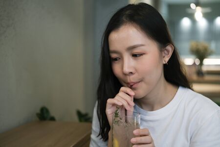 Asian girl drinking lemon soda in cafeの写真素材