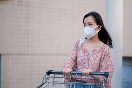 Asian girl wear surgical mask to protect the Covid-19 in supermarket, New normal lifestyleの写真素材