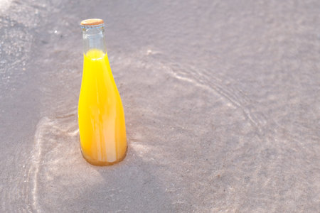 A bottle of orange juice on the beach, summer backgrounds conceptの写真素材