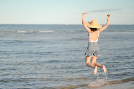 Asian woman with pink swimsuit jumping on the beachの写真素材