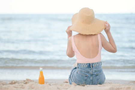 Asian woman with pink swimsuit and Straw hat on the beach