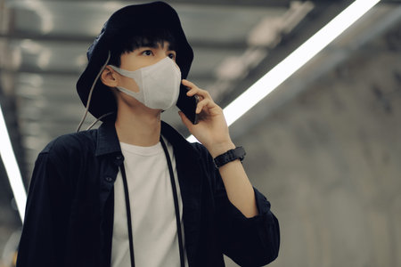 Asian man using smartphone with medical face mask to protect the Covid-19, new normal lifestyle