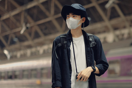 Asian travelers men and camera in train station with medical face mask to protection the Covid-19,...