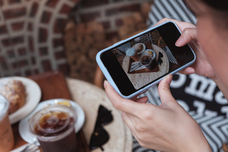 A girl take a picture of coffee and cake by smartphone in cafeの写真素材