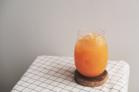 A glass of iced Orange juice on wood plateの写真素材