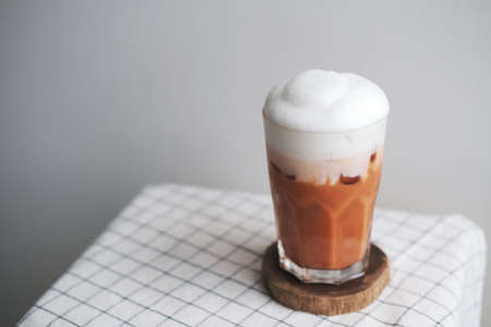 A glass of iced milk tea on wood plateの写真素材