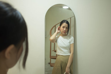 Before going to work, an Asian woman gets dressed in front of a mirror.の写真素材
