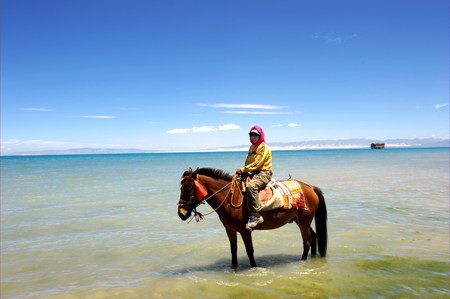 Qinghai Lake with a woman riding horseのeditorial素材