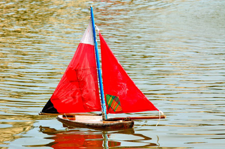 France, Paris: Little toy boat with red sail, green water and red sails