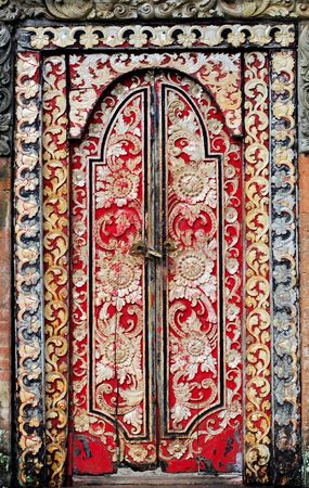 Indonesia, bali: red painting and carved  door; a typical decoration in southeast-asia の写真素材