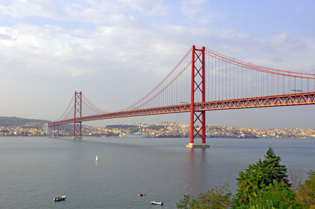 Portugal, Lisbon: 25 abril Bridge; blue water and red bridge , a typical view of lisbon
