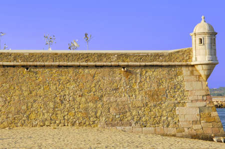 Portugal, area of Algarve, Lagos: typical architecture. Blue sky and yellow stone fortress; detail of one tower of control の写真素材