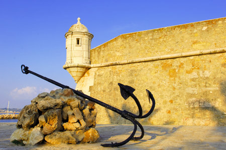 Portugal, area of Algarve, Lagos: typical architecture. Blue sky and yellow stone fortress; detail of one tower of control and of one anchor の写真素材