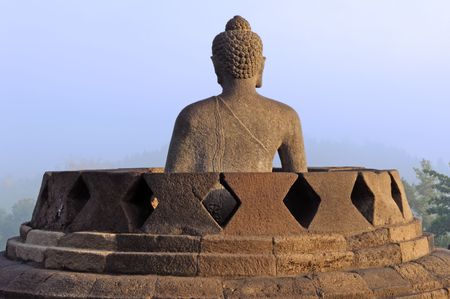 Indonesia, java, Borobudur: a beautifull stone seat buddha in meditation facing to the  sunrise at the most famous asiatic temple, the bigest buddhist temple from the first millenium in the world の写真素材