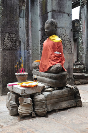 Cambodia Angkor, The Bayon was constructed during the reign of Jayavarman VII and Jayavarman VIII (13th century). The temple is one of the most enigmatic religious constructions in the world. Here a seated buddha statue inside the templeの写真素材