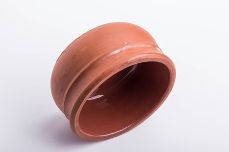 A brown bowl made out of clay, on it's side, on a white surface.の写真素材