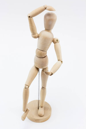 A wooden mannequin in a ballet pose, on it's base, on a white surface.の写真素材