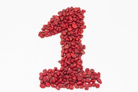 The number one made by little red stones, put one next to the other, on a white surface.