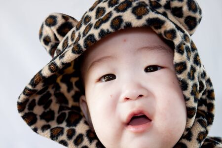 a beautiful smiling baby wrapped in a furry tiger skinの写真素材