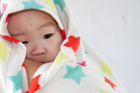 a beautiful smiling baby wrapped in a furry white blanket or towelの写真素材