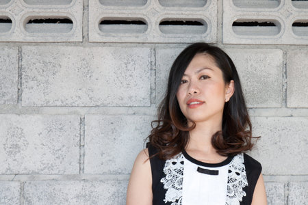 Beautiful Asian young businesswoman standing with hands folded against white backgroundの写真素材