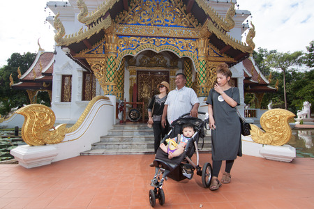 Ornate Buddhist temple complex featuring stone lions & a gilded chedi amid tropical greenery.のeditorial素材