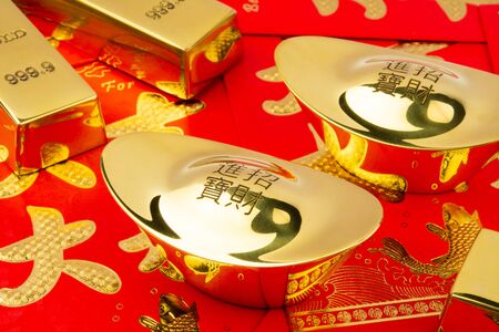There are some gold ingots on the table covered with red envelopesの写真素材