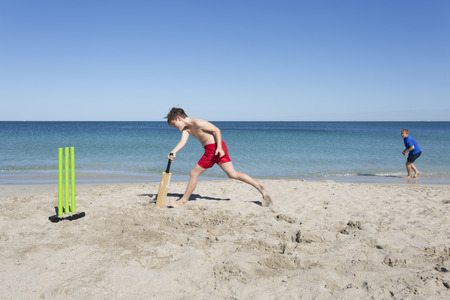Two siblings or friends playing Beach Cricket.の写真素材