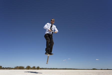 A businessman jumping with a pogo stick.の写真素材