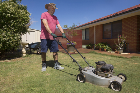 A man mowing the lawn in his back yard.の写真素材