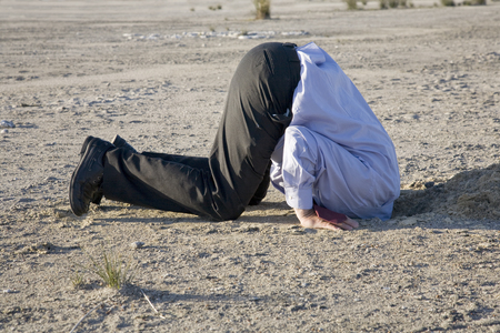 A powerful denial concept, man with his head in the sand.の写真素材