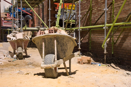 A large construction site with a whellbarrow and scaffolding.
