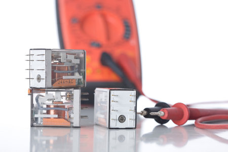 Electrical control relays and a multi-meter on white.