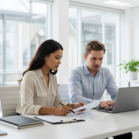 Two professionals collaborating on a project at a modern office deskの素材