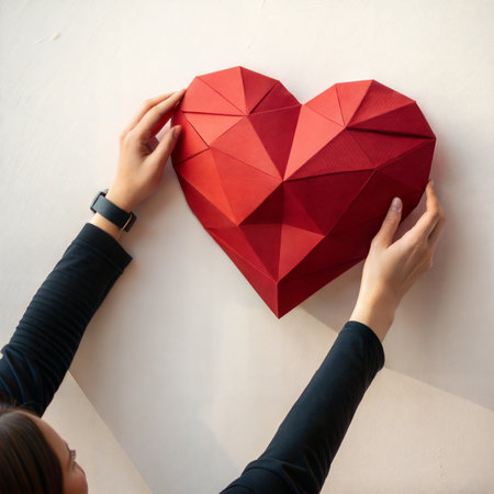 Red paper heart in hands of a girl on a white background.の素材