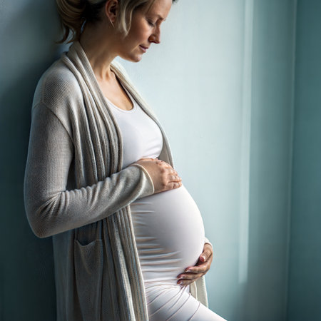 Pregnant woman holding her belly and looking out the window.の素材