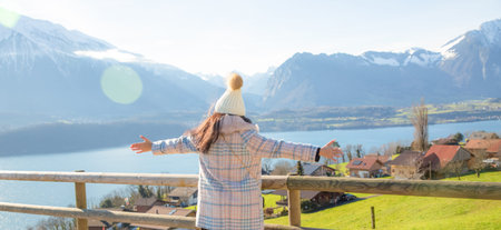A picture of a beautiful woman looking at a mountain with a lot of snow happily as a holiday vacation and enjoying nature in the mountains. The famous GRINDELWALD-FIRST of Switzerland.の写真素材