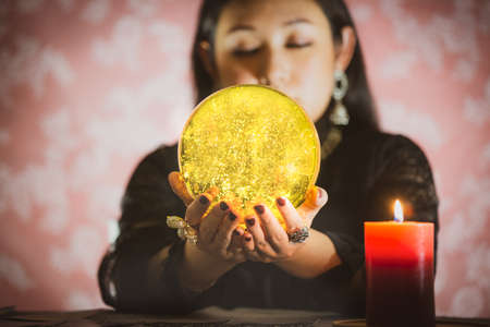 A picture of a woman holding a candle to perform magic rituals and mysteries about superstition in the concept of Divine magic & occultism on the old wooden table.の写真素材