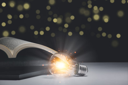 Hand held light bulb on the Book and light bulb style bokeh vintage dark background,Concept The idea...