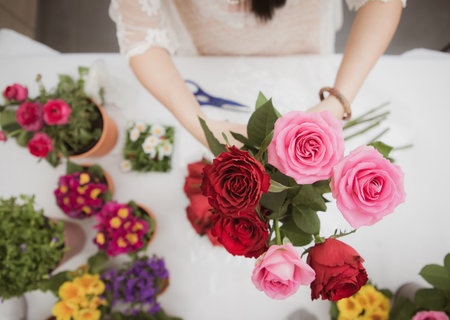 Woman Preparing to trim red and pink roses and beautiful flower arrangements in the home, flower arrangements with vase for gift-giving for Valentine's Day and Business in the family on the on tableの写真素材