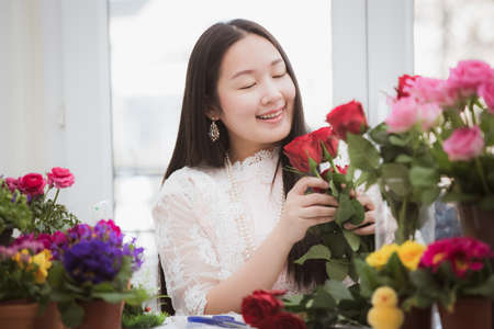 Woman Preparing to trim red and pink roses and beautiful flower arrangements in the home, flower arrangements with vase for gift-giving for Valentine's Day and Business in family on the on tableの写真素材
