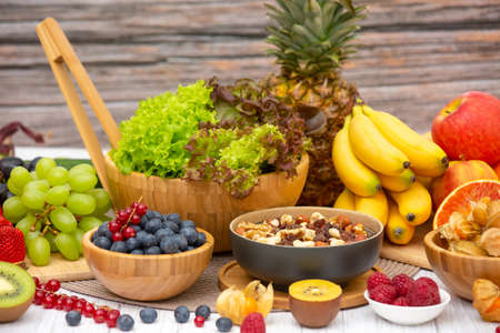 Group Fruits Breakfast mixed vegetables with salad bowl, nuts bowl, strawberry, banana, and pineapple, orange juice,  vitamin c in food  nature for health and diet in the top view on the wood table.の写真素材