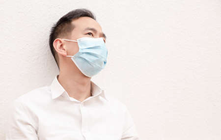 The image of a young Asian man wearing a mask to prevent germs, toxic fumes, and dust. Prevention of bacterial infection in the air around in the white background.の写真素材