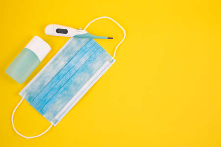 Mask for wearing germ protection Coronavirus or covid19 and gel alcohol or hand sanitizer bottle for washing hand, fever monitor for doctor and hospitals in isolated on yellow background.の写真素材