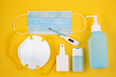 Mask for wearing germ protection Coronavirus or covid19 and gel alcohol or hand sanitizer bottle for washing hand, fever monitor for doctor and hospitals in isolated on yellow background.の写真素材