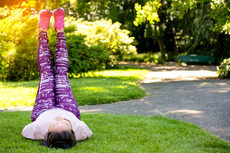 young Asian woman doing yoga fitness exercises in the nature park, Exercise for health or warm-up...