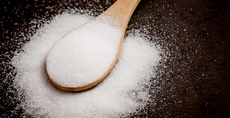 White sea salt for cooking in a small glass bottle. On the salt background, write stop. Concept for healthの写真素材