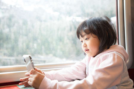 Asian girls are enjoying the natural view from the window on the train happily and traveling on a vacation in Switzerland and planning travel by train.の写真素材